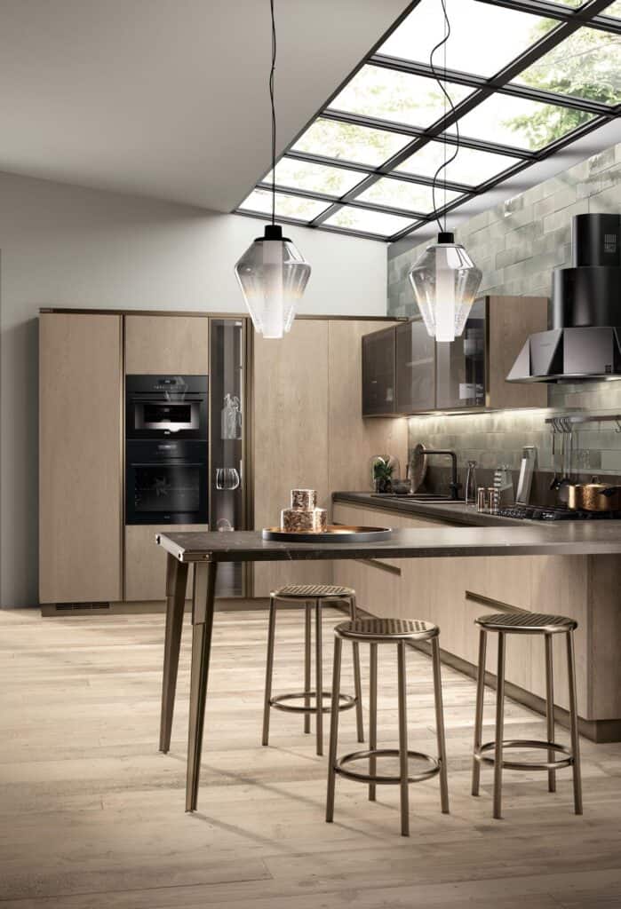 Modern kitchen with wooden cabinets, an island with bar stools, and pendant lights under a skylight.
