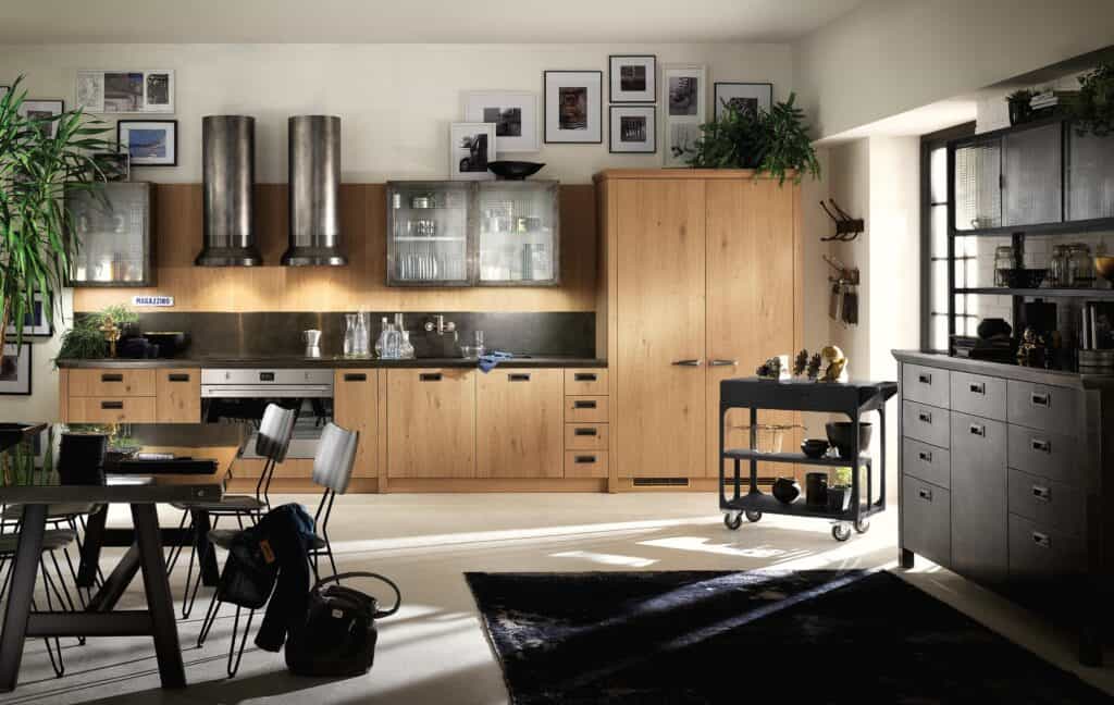 Modern kitchen with wooden cabinets, steel appliances, framed pictures on the wall, and a mix of plants and decorative items.
