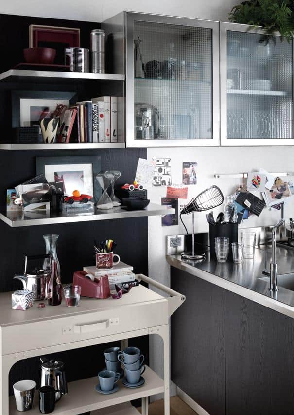Stylish kitchen corner with metal and wooden shelves, various decorative items, books, glassware, and kitchen utensils.