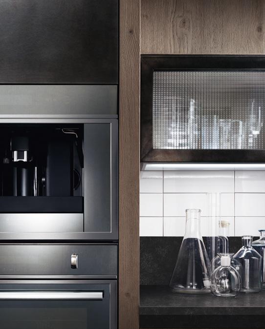 Modern kitchen with built-in appliances, glassware on the counter, and white tile backsplash.