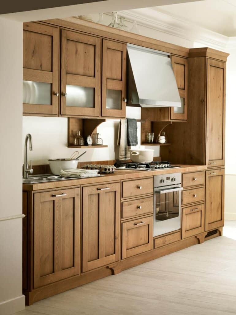 Wooden kitchen cabinets with a built-in oven, gas cooktop, range hood, and sink.