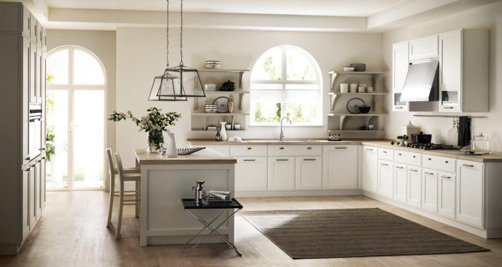 Modern kitchen with white cabinets, wooden countertops, an island with chairs, open shelving, and a large arched window.