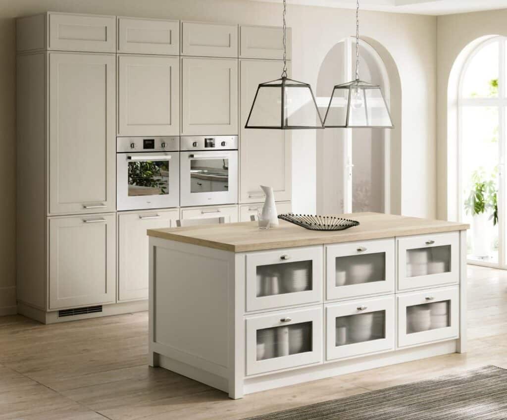 Modern kitchen with white cabinetry, built-in ovens, a wooden island, and pendant lights.