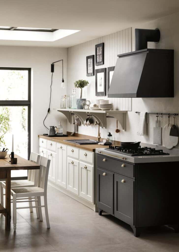 Modern kitchen with white cabinets, a wooden countertop, black range hood, and decorative wall art.