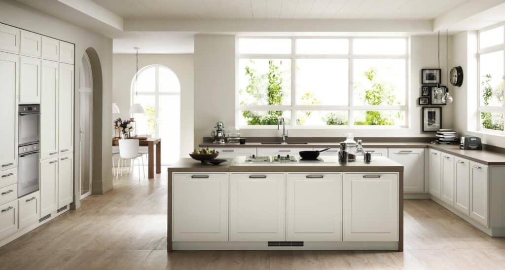 Modern kitchen with white cabinetry, a central island, and large windows.