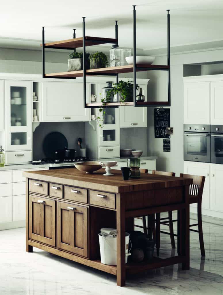 Modern kitchen with a wooden island, white cabinets, hanging shelves with plants, and marble flooring.