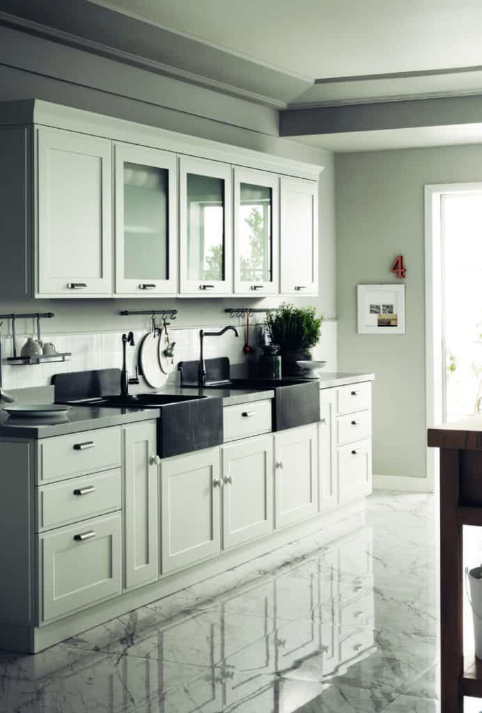 Modern kitchen with white cabinets, black countertops, a double farmhouse sink, and a glossy marble floor.