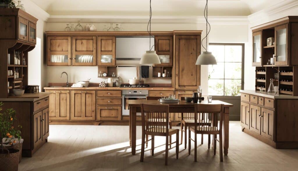 Cozy kitchen with wooden cabinets, a dining table with chairs, hanging pendant lights, and a window allowing natural light.