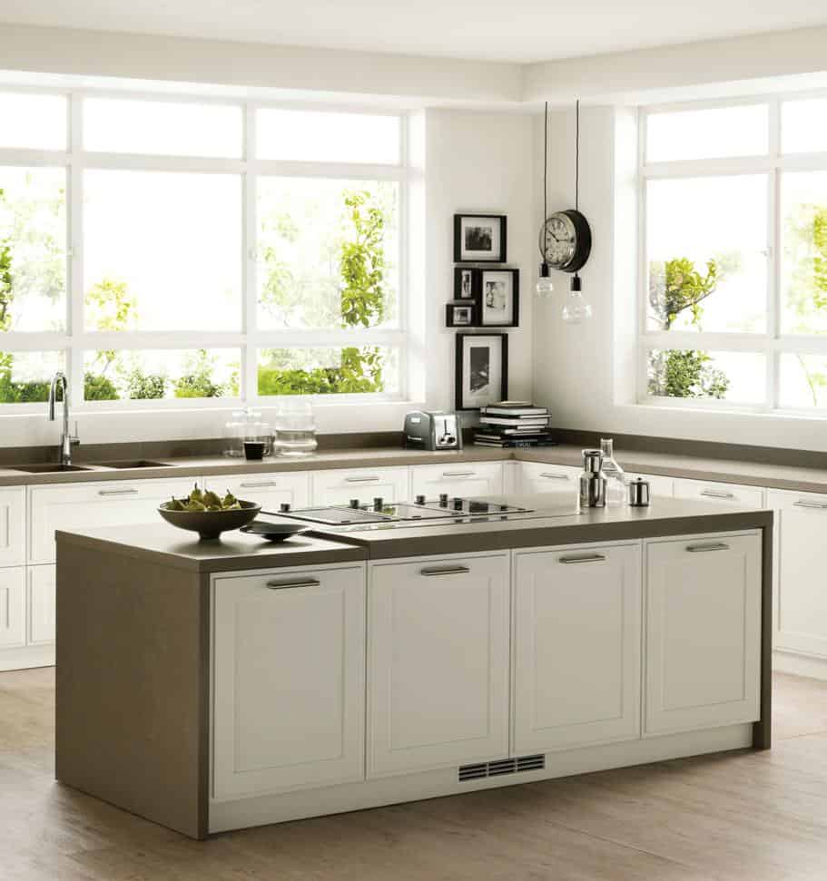 Modern kitchen with large windows, white cabinetry, a central island with a stovetop, and minimalist decor.