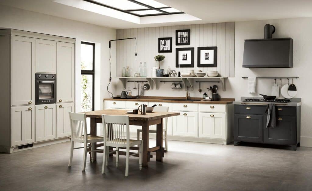 Modern kitchen with white cabinets, wooden table and chairs, black stove and range hood, and decorative wall art.