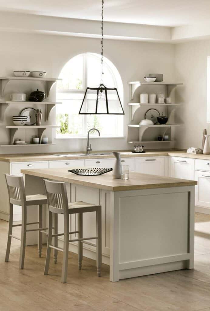 Modern kitchen with white cabinetry, a wooden countertop island, pendant lighting, and open shelving displaying dishes and decor.