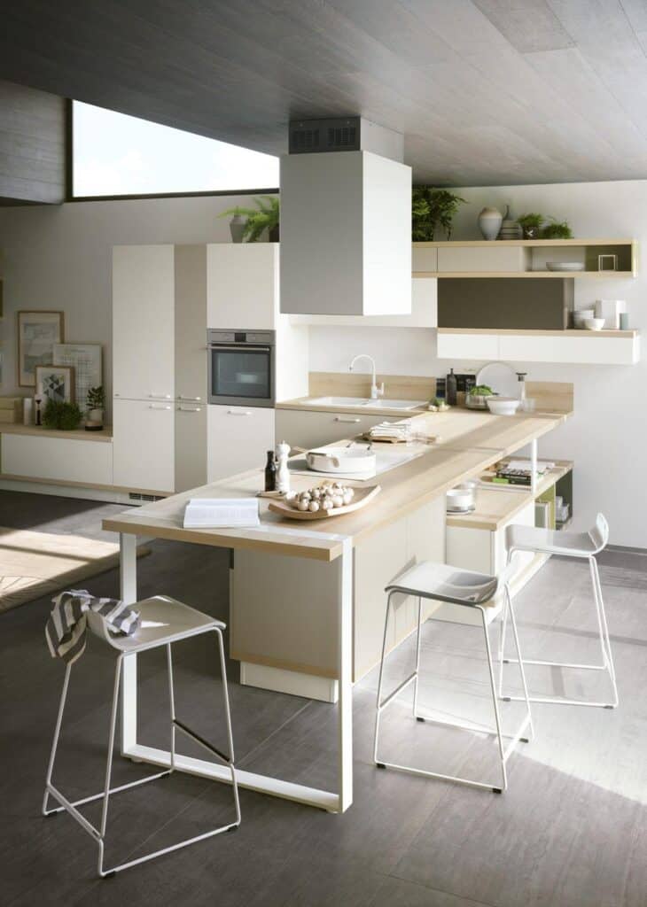Modern kitchen interior with white cabinets, a central island, bar stools, and potted plants.