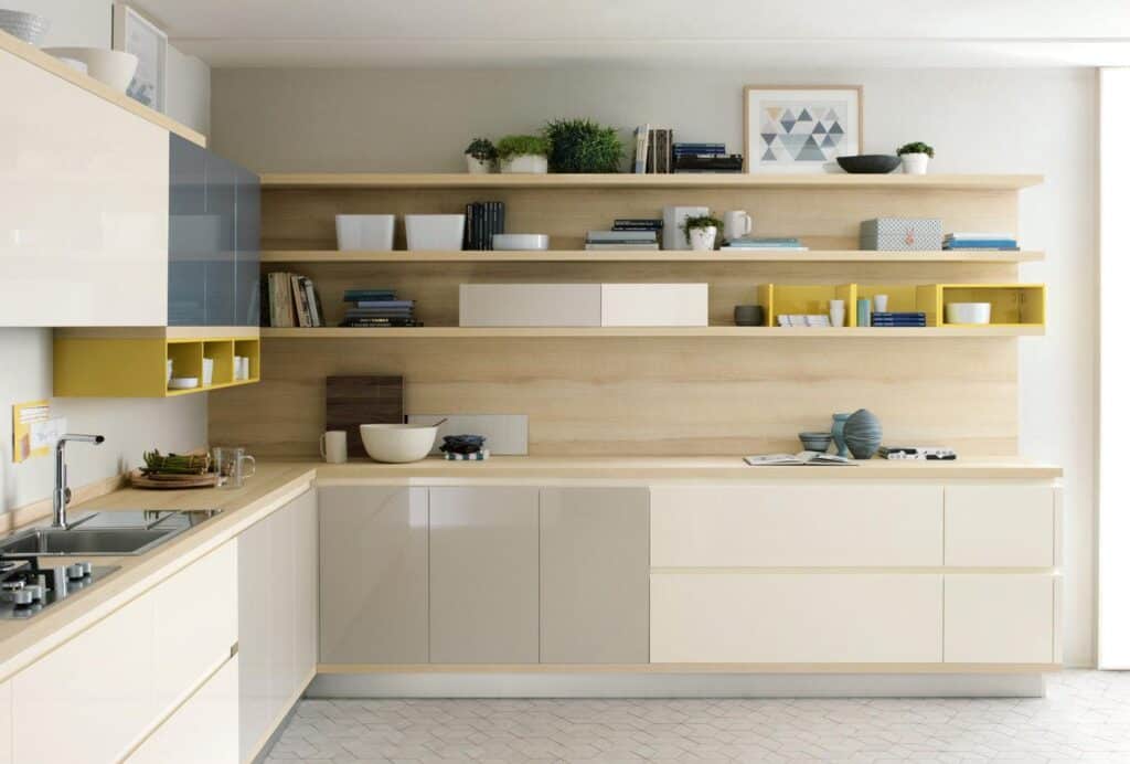 Modern kitchen with light wood cabinetry, open shelving, and minimalistic decor, featuring plants, books, and plates.