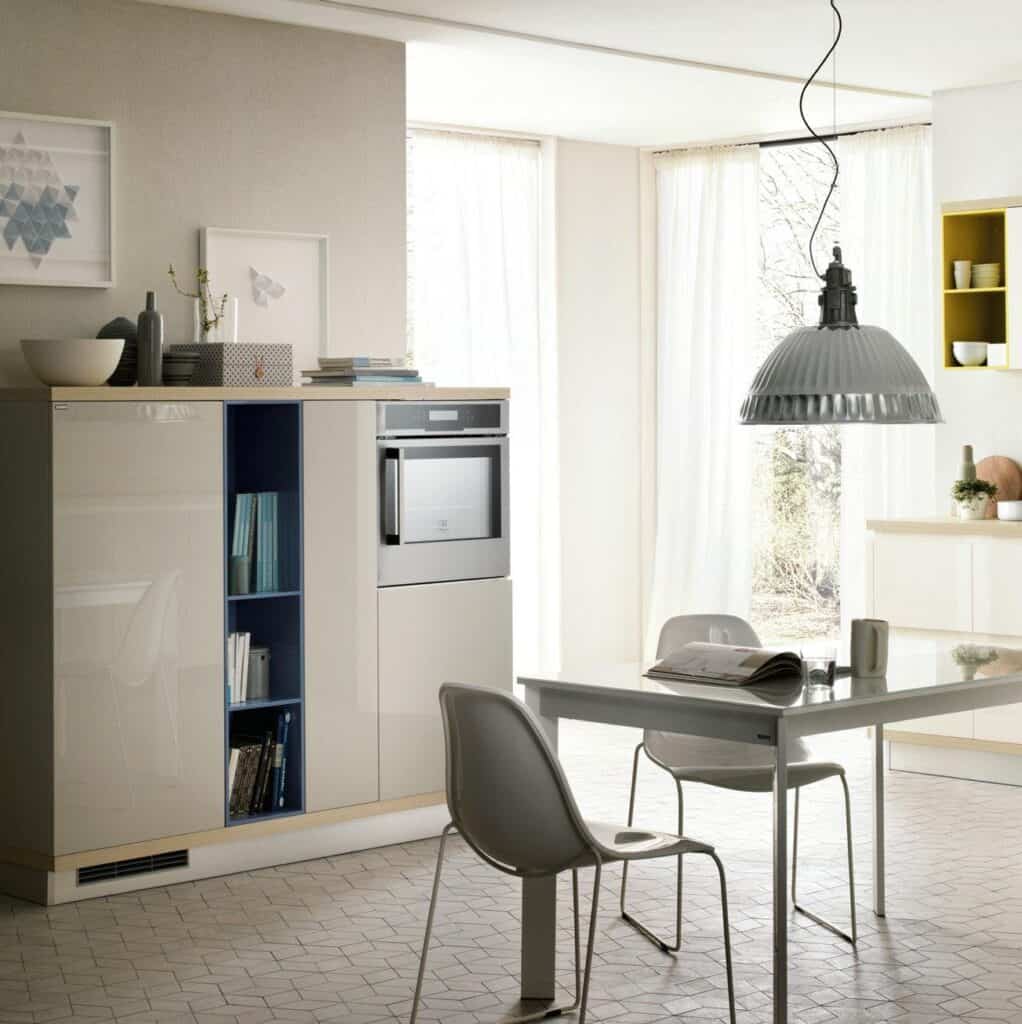 Modern kitchen interior with minimalist furniture, a hanging lamp, and natural light coming through large windows.