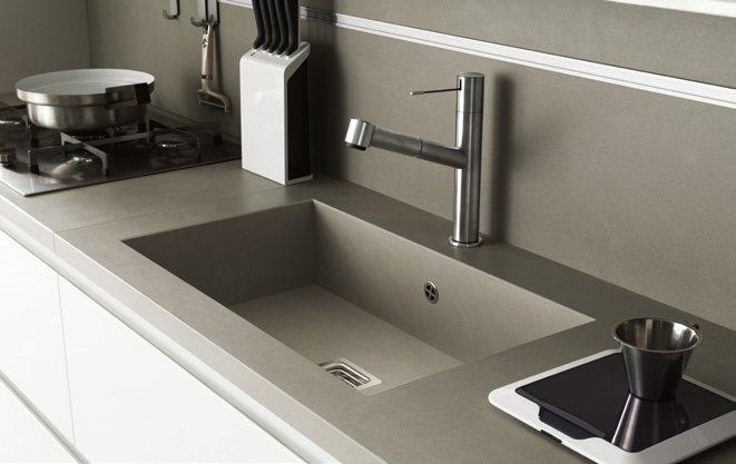 Modern kitchen countertop with an integrated sink, faucet, gas stove, knife block, and electronic scale.
