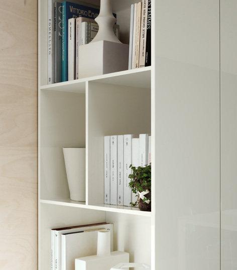White bookshelf with books, a white vase, and a small plant.