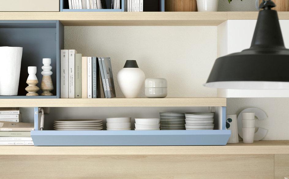Wooden shelves with books, decorative vases, and stacked white dishes, under a black hanging lamp.