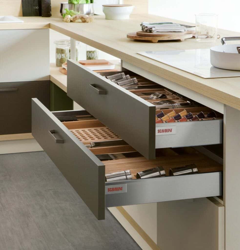 Kitchen with open drawers displaying organized cutlery, utensils, and coffee pods.