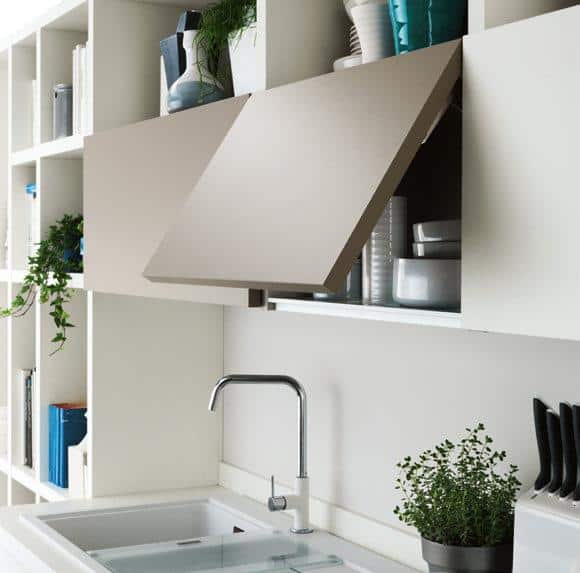 Modern kitchen with white cabinets, open shelving, a silver faucet, and green plants.