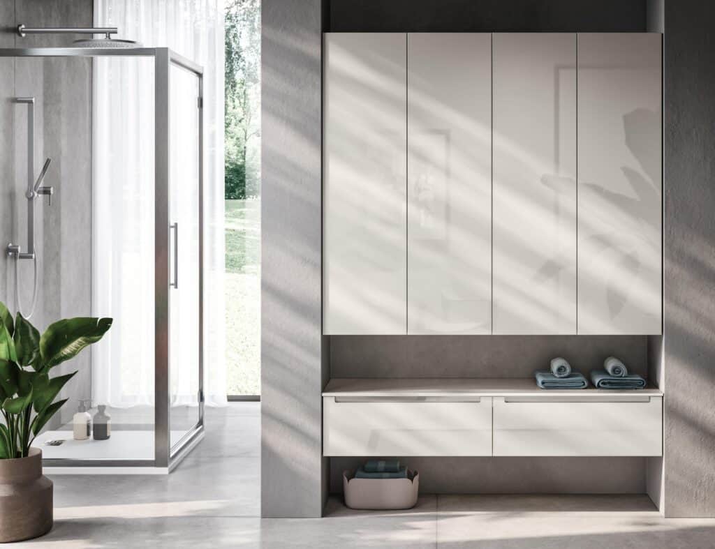 Modern bathroom interior with a glass shower, white cabinets, towels, and a potted plant.