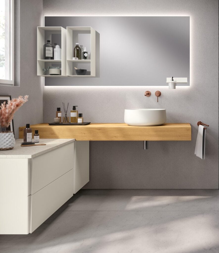 Modern bathroom interior with a floating wooden vanity, round white vessel sink, tall mirror with backlighting, open shelving with toiletries, and decorative items.