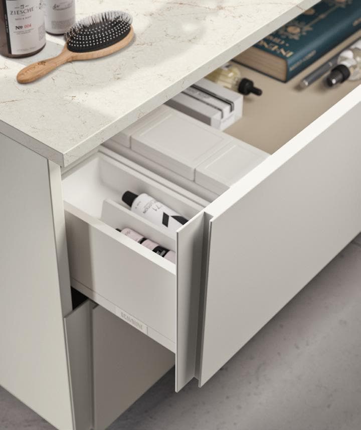 Open drawer in a bathroom vanity with neatly organized toiletries, a hairbrush, and other personal items on the countertop.