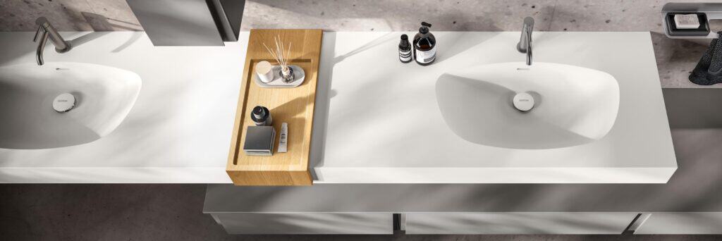 Modern double bathroom sink with a central wooden tray holding toiletries.