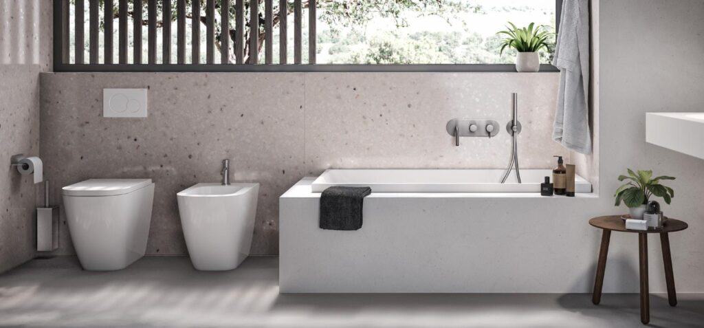 Modern bathroom with a toilet, bidet, bathtub, and a small wooden side table with plants, featuring a large window and minimalist decor.