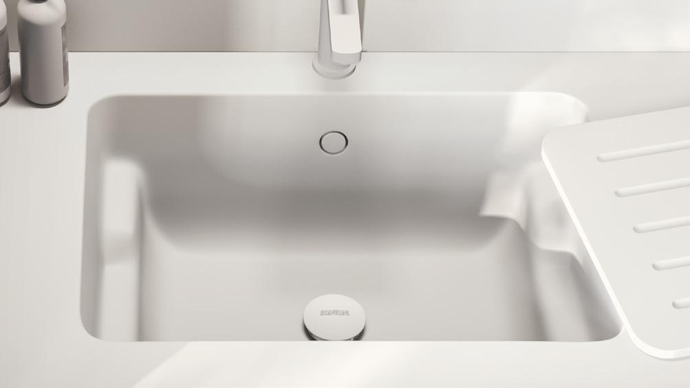 A modern white kitchen sink with a rectangular basin, accompanied by soap dispensers on the side.