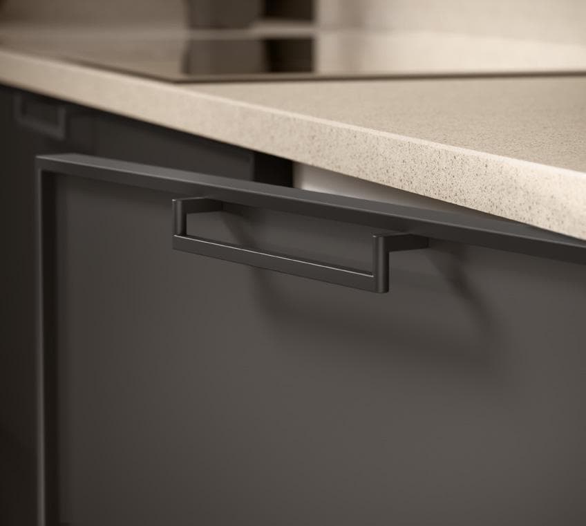 Close-up of a modern kitchen cabinet handle with a beige countertop above.