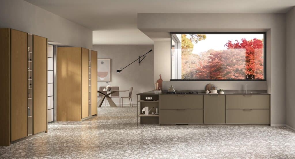 Modern kitchen interior with large window, wooden cabinets, neutral countertops, and patterned flooring, overlooking autumn trees.