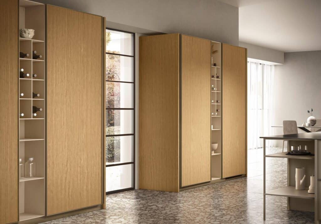 Modern kitchen with wooden cabinets and open shelving for wine bottles and dishes, featuring large windows and a marble-patterned floor.