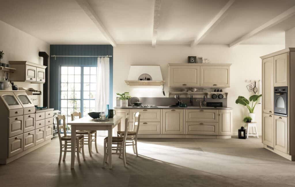 Spacious kitchen with cream-colored cabinetry, a dining table with chairs, large windows, and modern appliances, accented with plants and decor items.