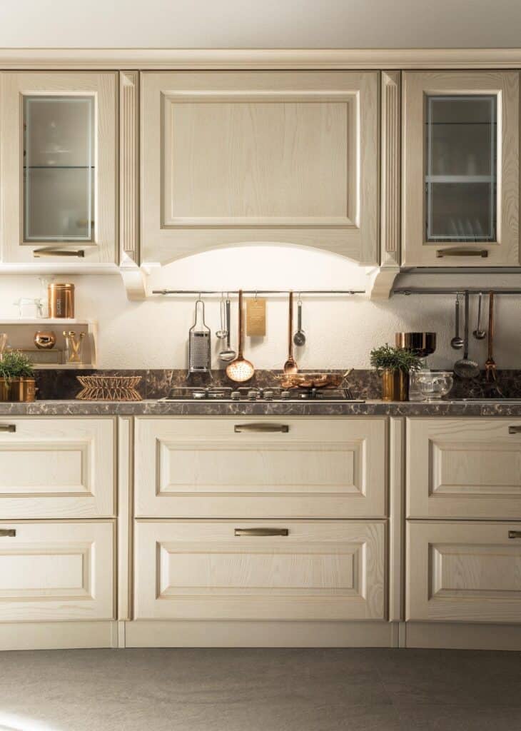 Elegant kitchen with light wood cabinets, dark marble countertop, and copper accents.