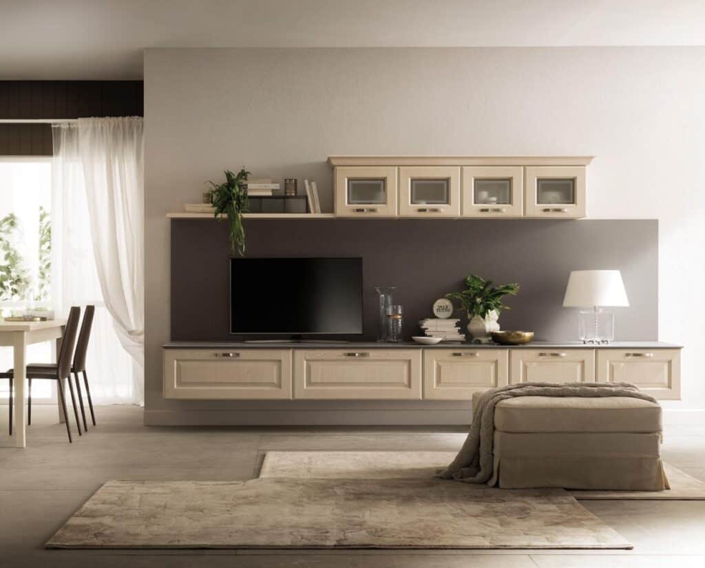 Modern living room with a wall-mounted TV unit, beige cabinetry, decorative plants, and a lamp, adjacent to a dining area.
