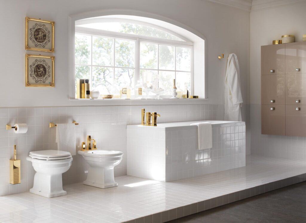Luxurious bathroom with gold fixtures, white tile, and a large arched window.