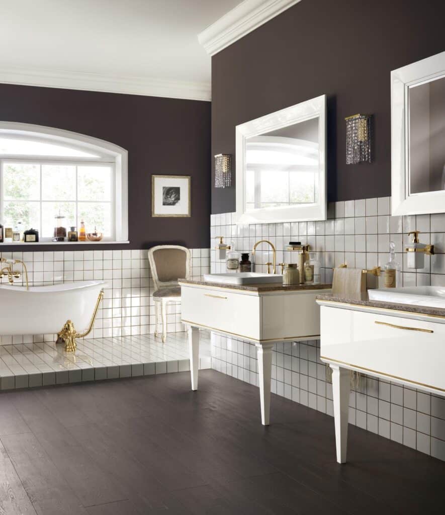 Elegant bathroom with a freestanding bathtub, gold fixtures, wall-mounted sinks, large mirrors, and dark wood flooring.