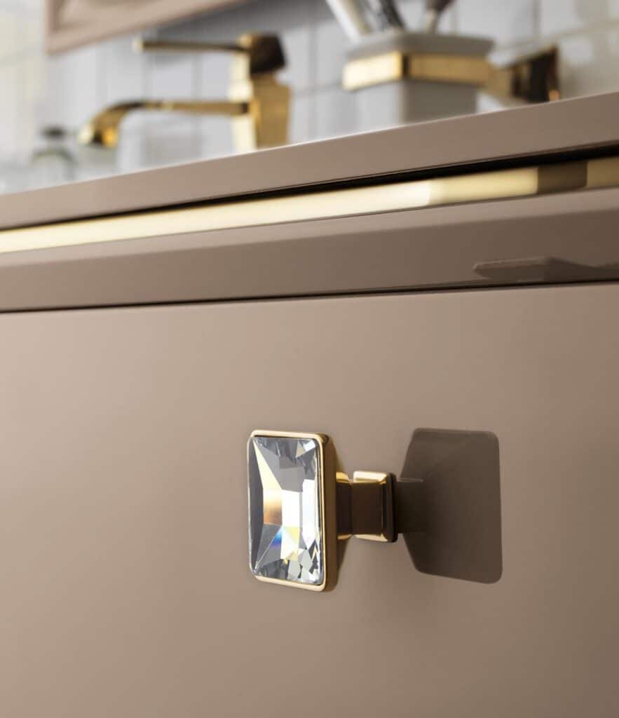 Close-up of a cabinet with a square crystal and gold handle.