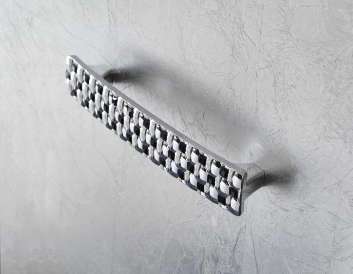 Chrome cabinet handle with a checkered pattern on a textured grey surface.