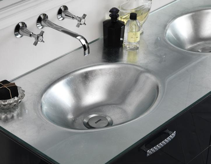 Modern bathroom with metallic sinks, a sleek countertop, wall-mounted faucets, and luxury toiletries.