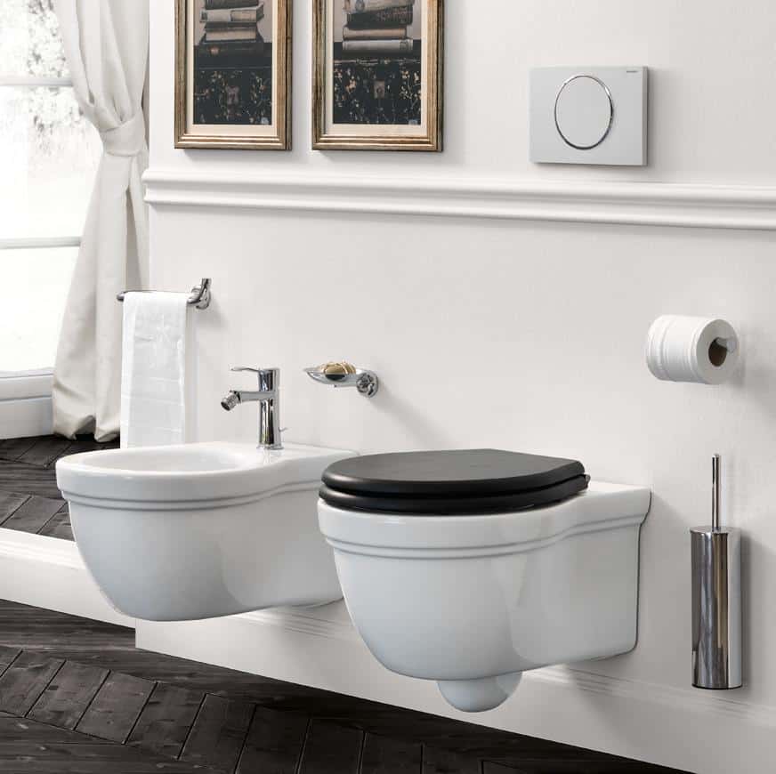 Modern bathroom with a white wall-mounted bidet and toilet, a black toilet seat, two framed pictures on the wall, a towel, toilet paper holder, and a toilet brush.