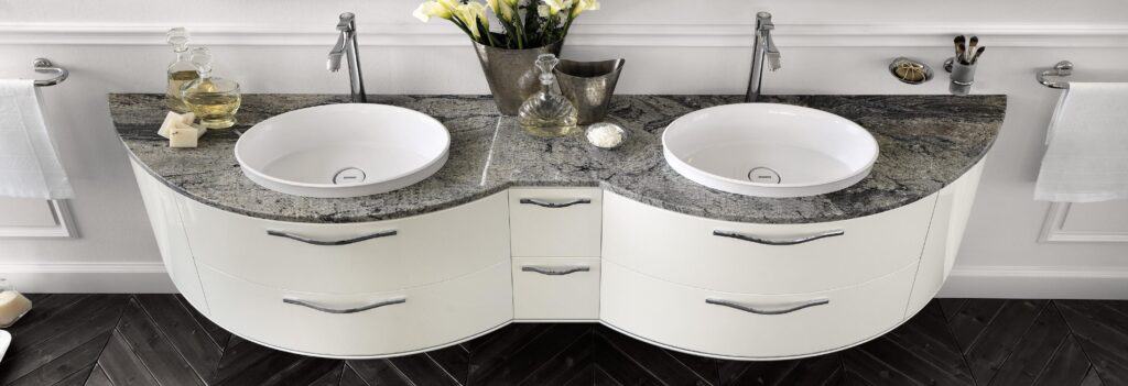 Double sink bathroom vanity with a curved design, featuring a granite countertop and white basins, complemented by chrome faucets and elegant handles.