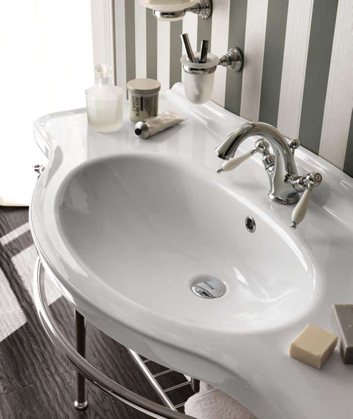 Elegant bathroom sink with chrome fixtures, striped wallpaper, and various toiletries on the counter.