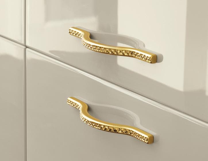 Gold handles on a white cabinet drawer.