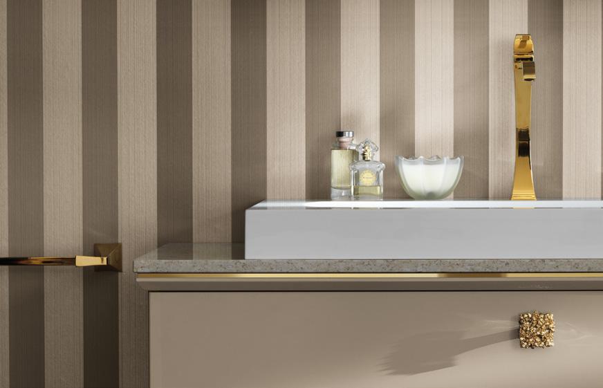 Bathroom sink area with gold faucet and beige striped wallpaper.