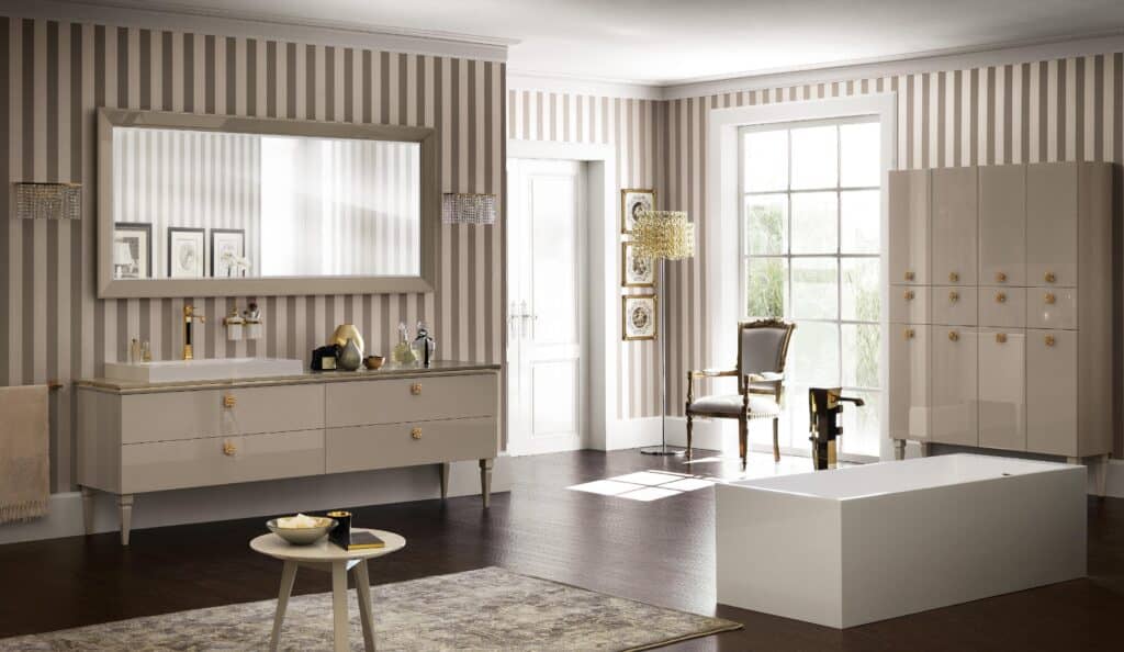 Elegant bathroom with striped wallpaper, large mirror, and a modern rectangular bathtub. The room features a pale vanity with gold accents, decorative chair, floor lamp, and dark wood flooring.