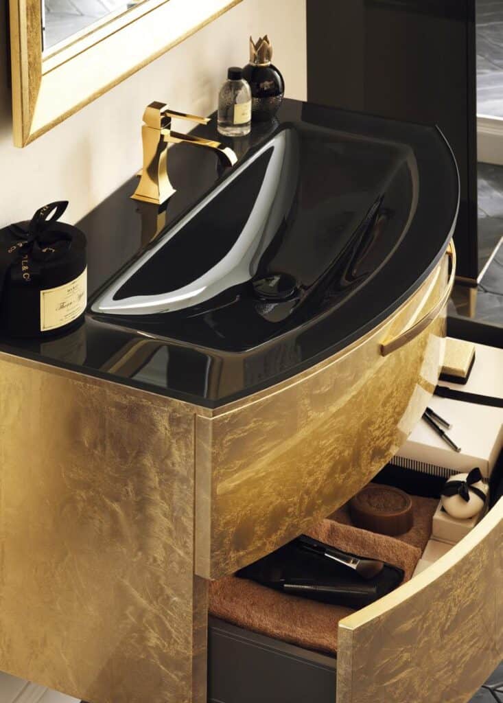 Luxurious bathroom vanity with a curved black sink, gold faucet, and gold leaf-finished cabinet.