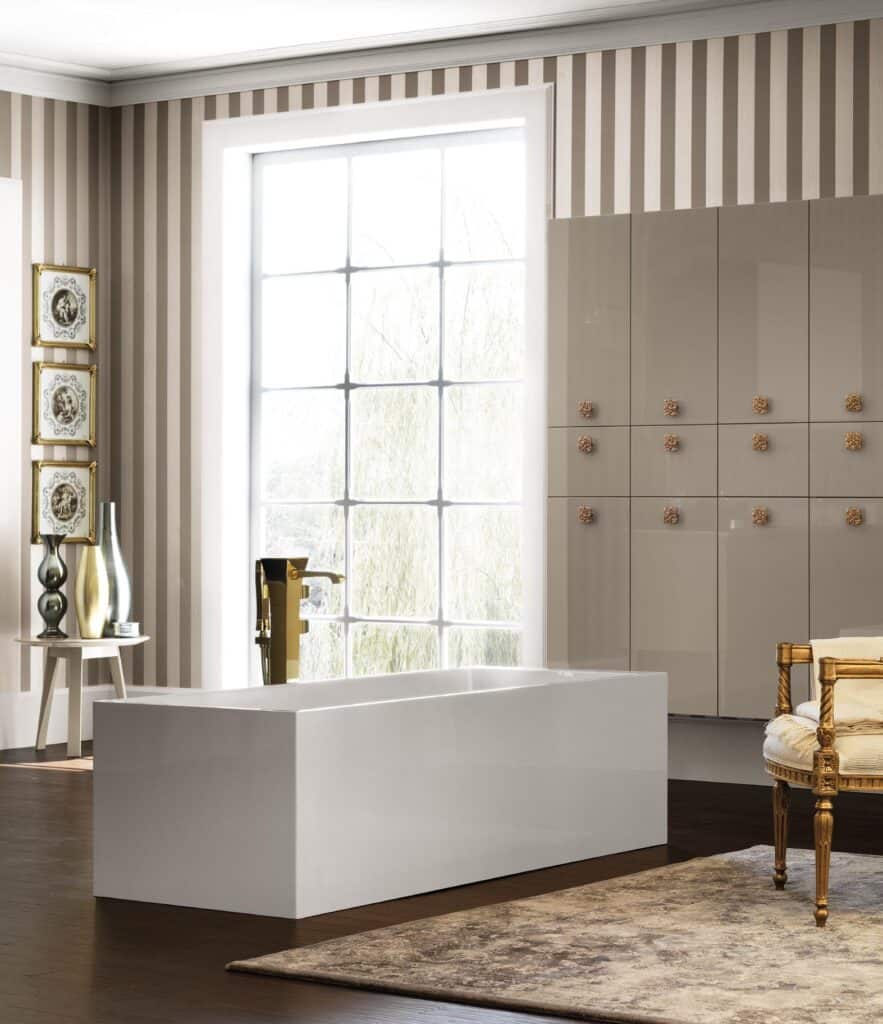 Elegant bathroom with a modern white bathtub, a large window with striped wallpaper, decorative wall art, and a gold-accented chair.