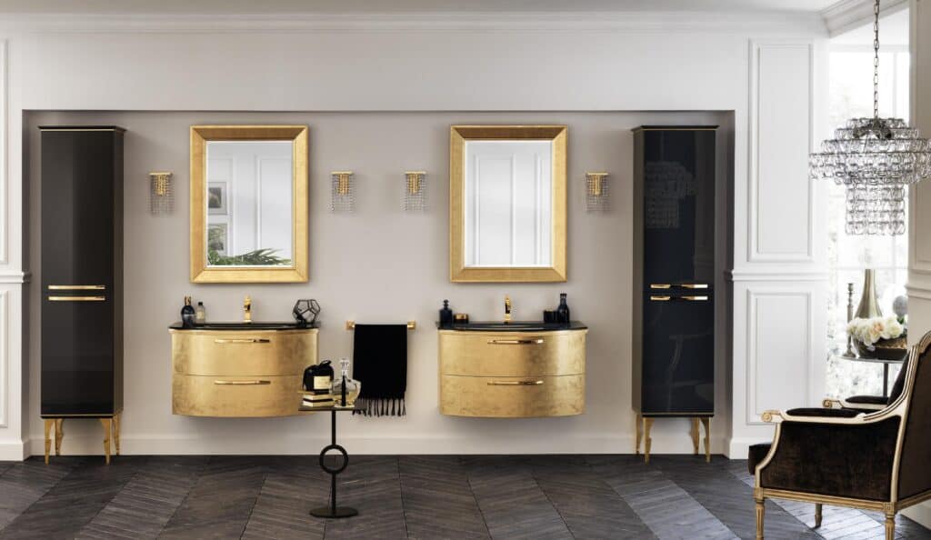 Luxurious bathroom with gold-accented vanities and mirrors, dark wood flooring, black cabinetry, and ornate chandelier.