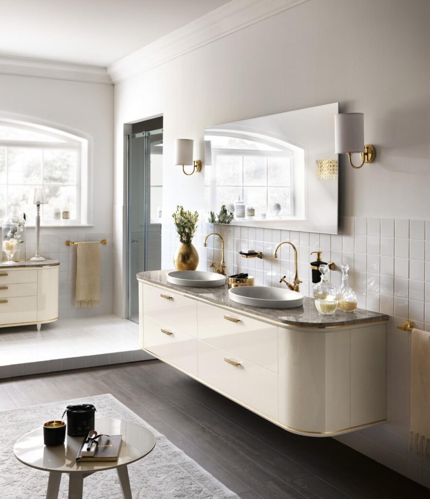 Elegant bathroom with double vanity sinks, gold fixtures, large mirror, and neutral decor.